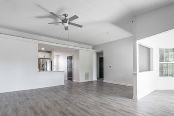 An empty living room and kitchen with a ceiling fan