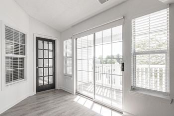 An empty living room with large windows and a door to a balcony