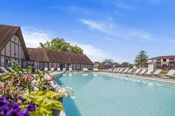 A large swimming pool with lounge chairs and a building in the background.