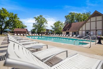 Resort style swimming pool with chaise lounge chairs and trees in the background