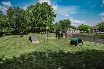 A playground with a slide and a green trash can
