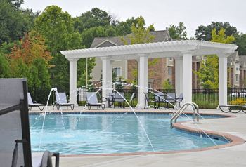 A swimming pool with a pergola and patio furniture