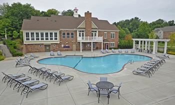 A swimming pool with chaise lounge chairs and a building in the background