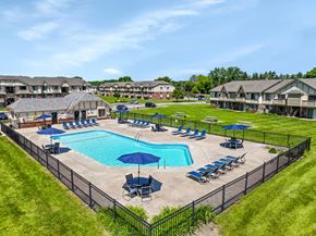 Essexville apartment for rent - A large swimming pool surrounded by a black fence and lounge chairs.