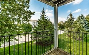 Merrillville apartment for rent - A balcony with a black railing and a view of a tree and a building in the background