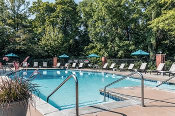 A swimming pool with chairs and trees in the background