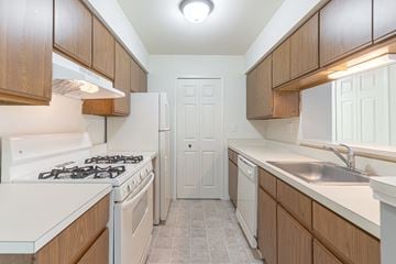 Farmington Hills apartment for rent - A kitchen with a white stove top oven and a white refrigerator.