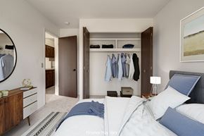 Westland apartment for rent - a bedroom with a large bed and a closet with clothes hanging on the wall at The Landings Apartments, Westland
