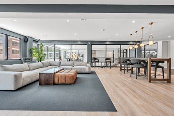 A modern living room with a grey sofa, a wooden coffee table, and a black rug.