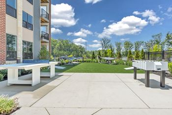 A sunny day at a residential complex with a white bench and a concrete path.