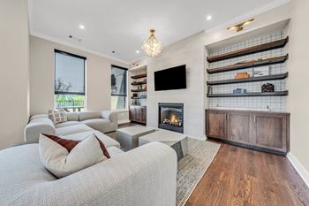 A modern living room with a grey couch and a fireplace.