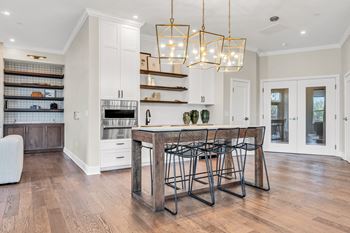 A kitchen with a wooden table and chairs and a hanging light fixture.
