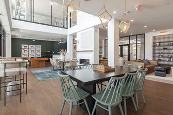 A modern dining room with a black table and green chairs.