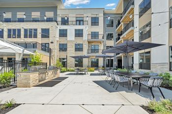 A sunny day at a modern apartment complex with a patio area.