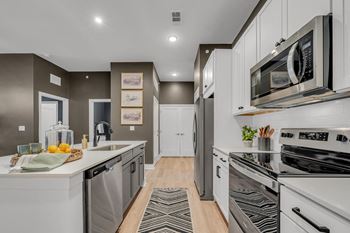 A modern kitchen with white appliances and a wooden floor.