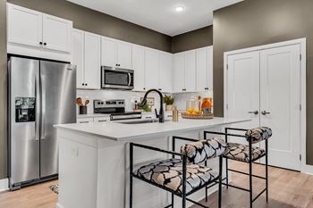 A kitchen with white cabinets and a stainless steel refrigerator.