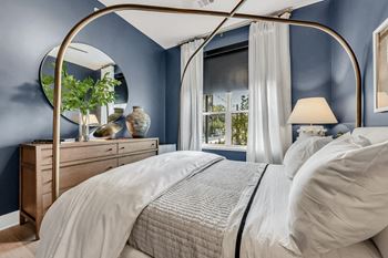 A bed with a canopy and a white bedspread in a room with blue walls.