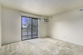 Kalamazoo apartment for rent - an empty living room with a sliding glass door to a balcony at Madeira Apartments, Kalamazoo, 49001