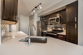 Crown Point apartment for rent - A modern kitchen with dark brown cabinets and a white countertop at Mallard Bay Apartments, Crown Point, Indiana