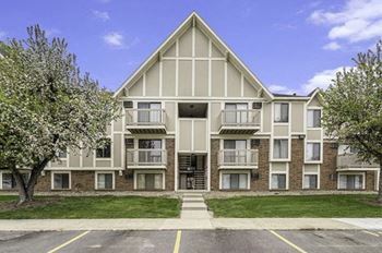 An exterior view of an apartment building with grass and trees