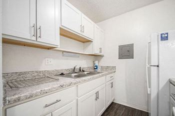 A kitchen with white cabinets and a sink and a refrigerator