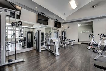 A spacious gym with a variety of equipment including treadmills, stationary bikes, and weight machines.