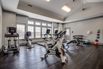 A gym with a variety of exercise equipment including treadmills, stationary bikes, and weight machines.