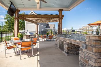 A patio with a stone fireplace and orange chairs.