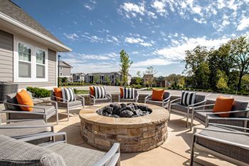A patio with a fire pit and chairs.