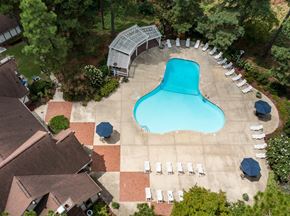 Fayetteville apartment for rent - A large blue kidney-shaped pool surrounded by white lounge chairs and umbrellas at Lake in the Pines, North Carolina, 28311