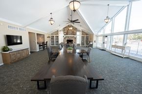 Wixom apartment for rent - A large wooden table is surrounded by chairs in a spacious room with a fireplace.