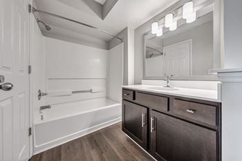 A bathroom with a white tub, sink, and mirror.