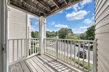 A balcony with a white railing and a view of the street below.