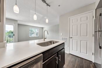 A modern kitchen with a white countertop and a stainless steel sink.