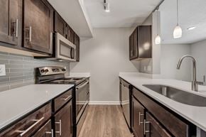 Roanoke apartment for rent - A kitchen with dark wood cabinets and a white countertop. at Sunscape Apartments, Roanoke, Virginia