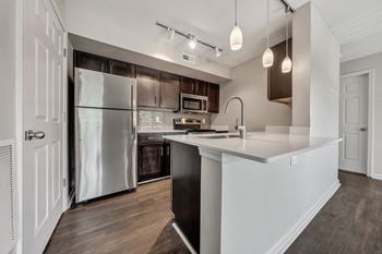 A modern kitchen with a refrigerator, microwave, and oven.