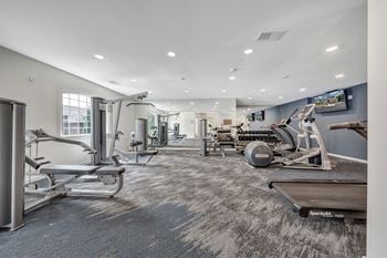 A spacious gym with a variety of equipment including treadmills, stationary bikes, and weight machines.