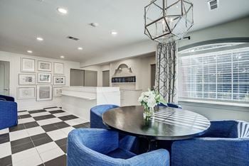 A black and white checkered floor in a room with blue chairs and a round table.