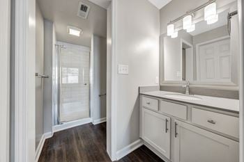 A bathroom with a sink, mirror, and a shower with a glass door.