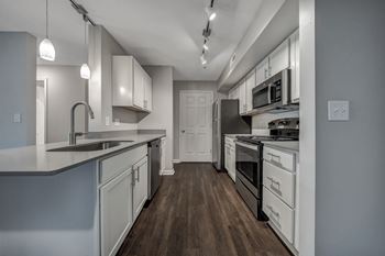 A modern kitchen with white cabinets and a wooden floor.