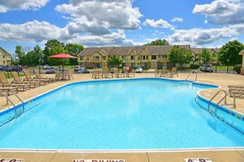A swimming pool with chaise lounge chairs and a building in the background