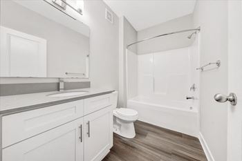 A white bathroom with a toilet, sink, and bathtub.