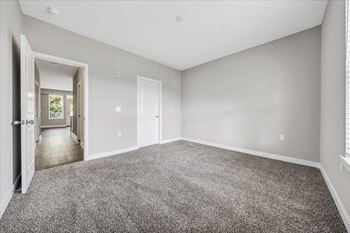 A spacious room with grey carpeting and white walls.