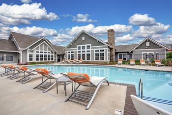 A pool with chairs and a building in the background.