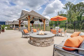 A patio with a fire pit and chairs.