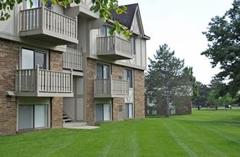 An apartment building with balconies and a green lawn