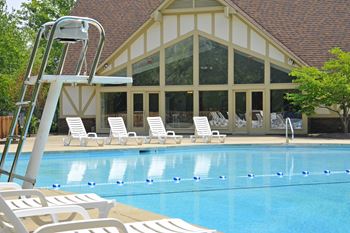 A swimming pool with chaise lounge chairs and a lifeguard tower in front of a building