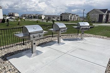 A row of stainless steel bbq grills on a concrete slab