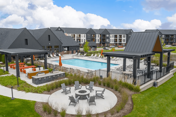 An aerial view of a resort style pool with lounge chairs and a fire pit