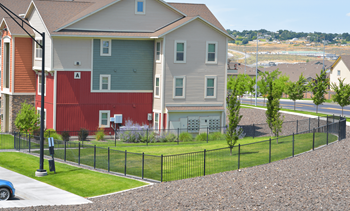 An apartment building with a red and gray garage and a black fence
